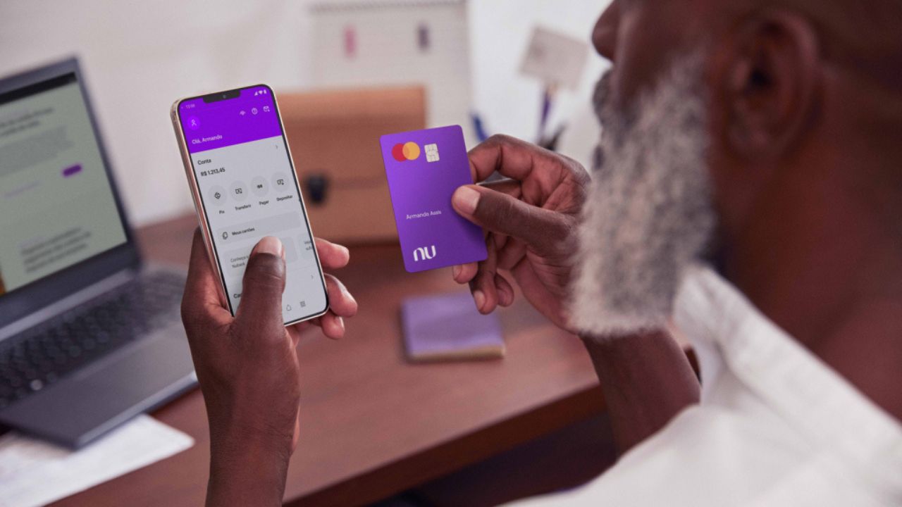 Homem negro idoso segura o cartão do Nubank
